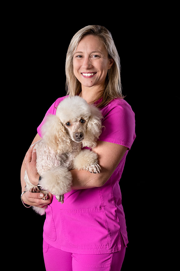 groomer holding a small white poodle