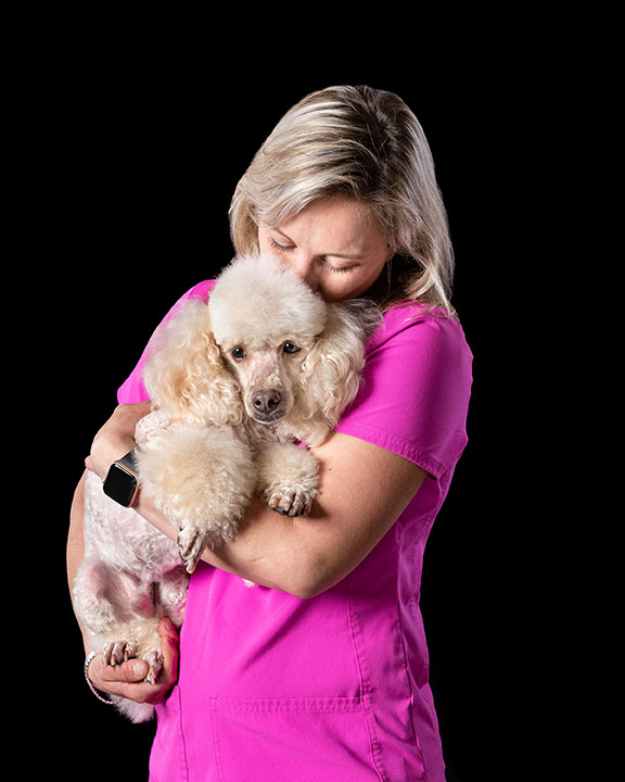 groomer holding a small white poodle