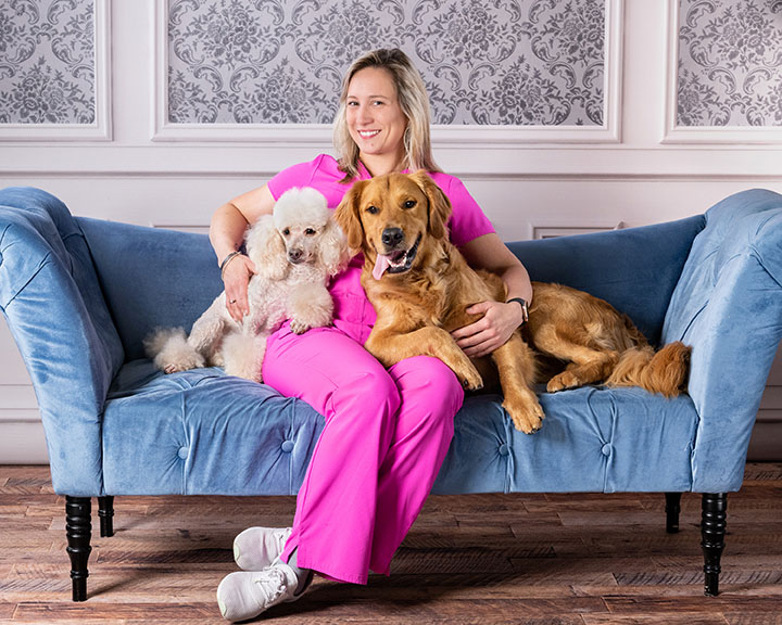 groomer sitting with two dogs on a couch
