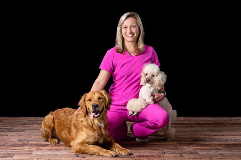 groomer sitting with two dogs